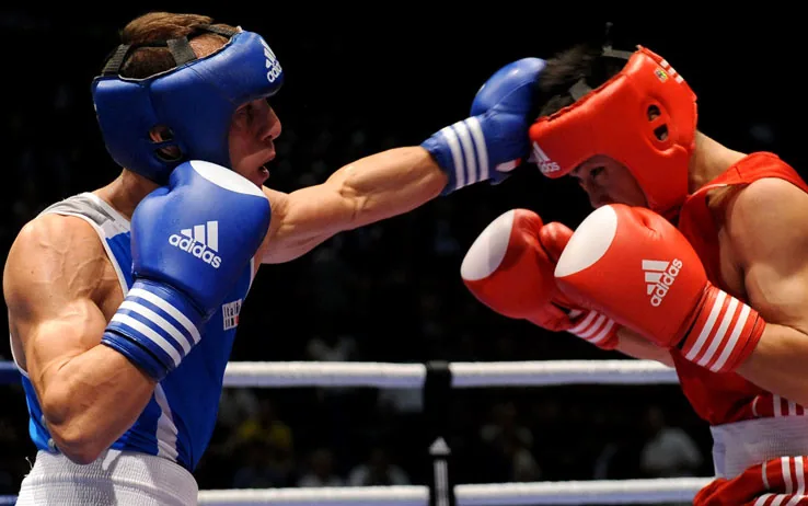 Deux boxeurs amateurs casqués échangent des coups sur le ring